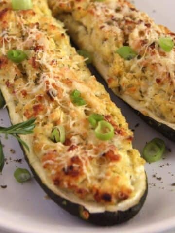 two vegetarian stuffed zucchini boats with grains, cheese and herbs.