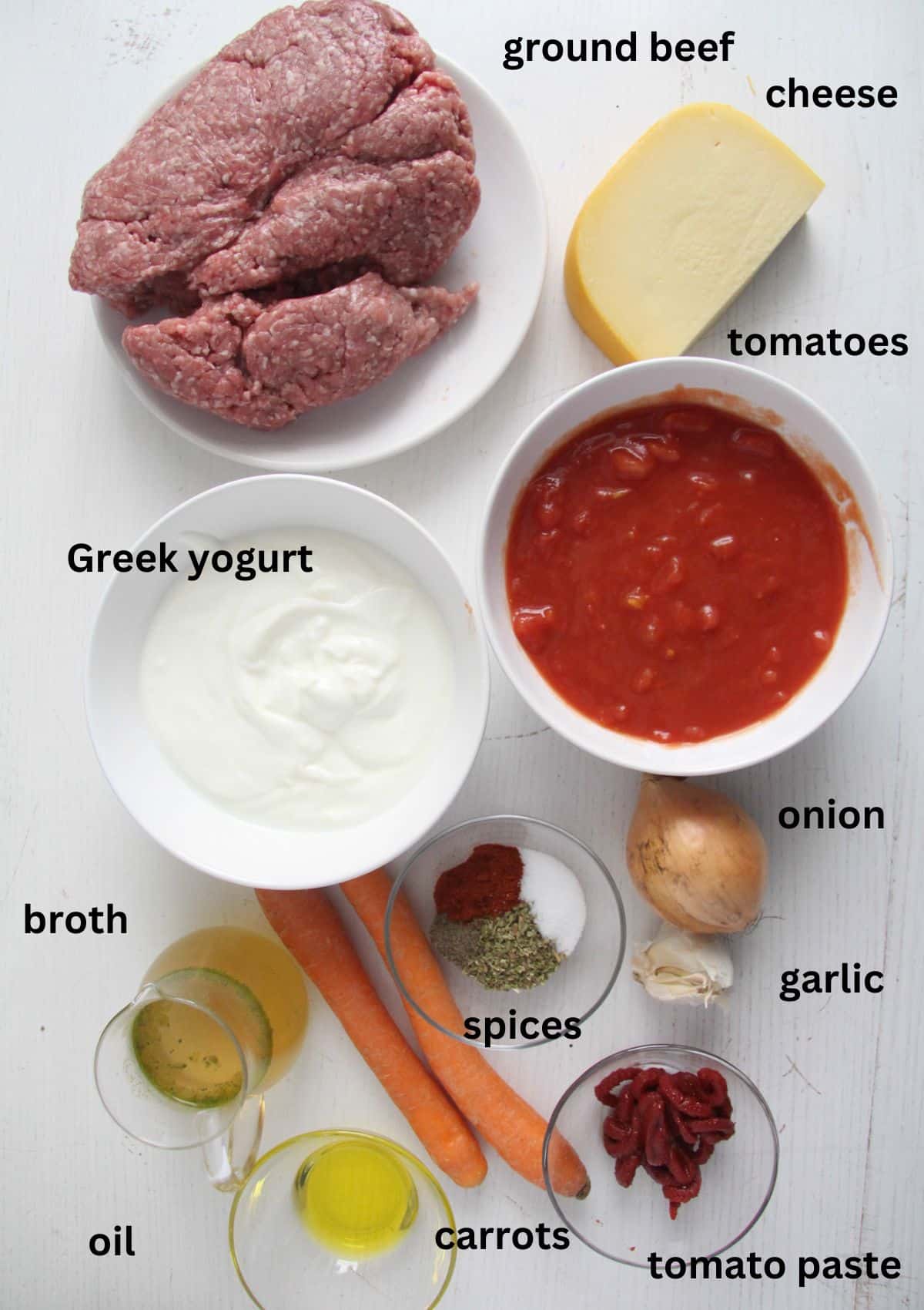 ingredients for making lasagna with yogurt sauce, ground beef, tomatoes and cheese.