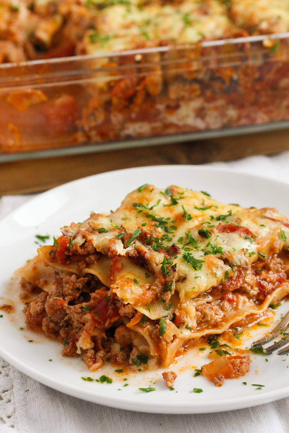 slice of yogurt lasagna with bolognese sauce and the whole dish behind it.