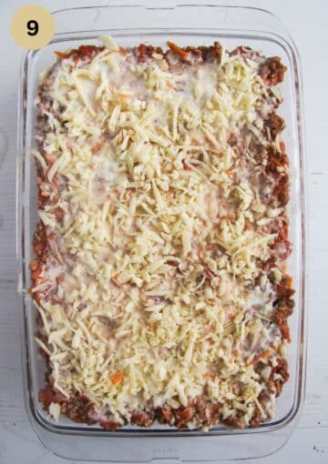 unbaked lasagna sprinkled with grated cheese.