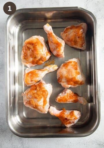 chicken thighs and legs topped with mango chutney in a roasting pan.