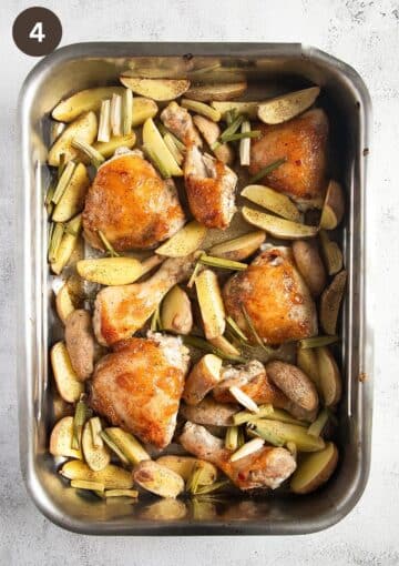 baked chicken thighs with potatoes and green onions in a roasting tin.