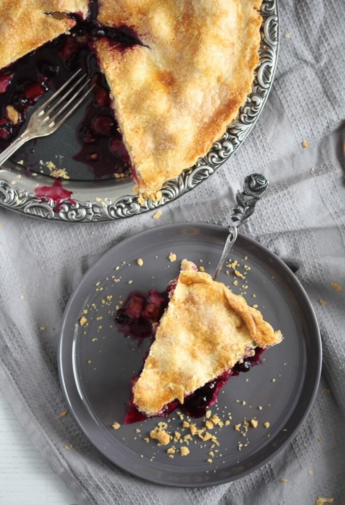 sliced blackberry rhubarb pie on a silver platter and a small plate