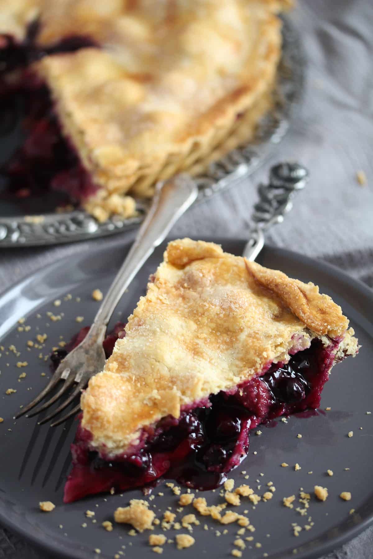 a slice of blueberry and rhubab pie on a small plate.