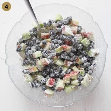 mixing chopped rhubarb and blueberries mixed with sugar and cornstarch to make pie.