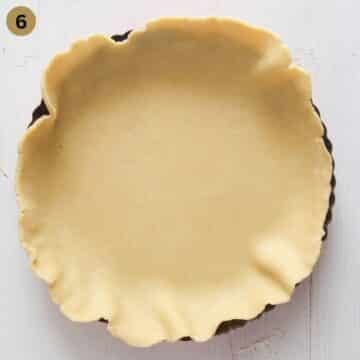 lining a pie dish with pie dough.