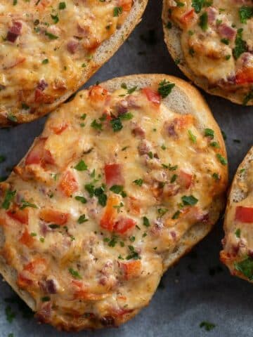 cheese topped rolls with ham, peppers and parsley.