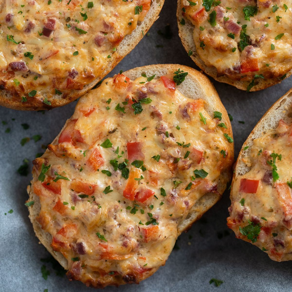 cheese topped rolls with ham, peppers and parsley.