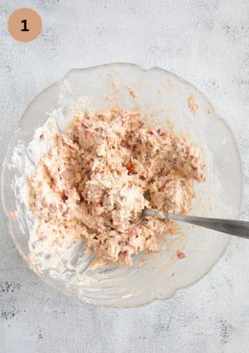 cheese, ham and sour cream mixture for topping bread in a bowl with a spoon.