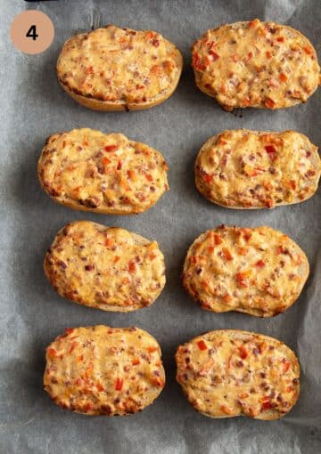 eight bread rolls topped with ham and cheese mixture on a baking sheet.