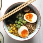 ramen with dashi broth topped with eggs, green onions and corn.