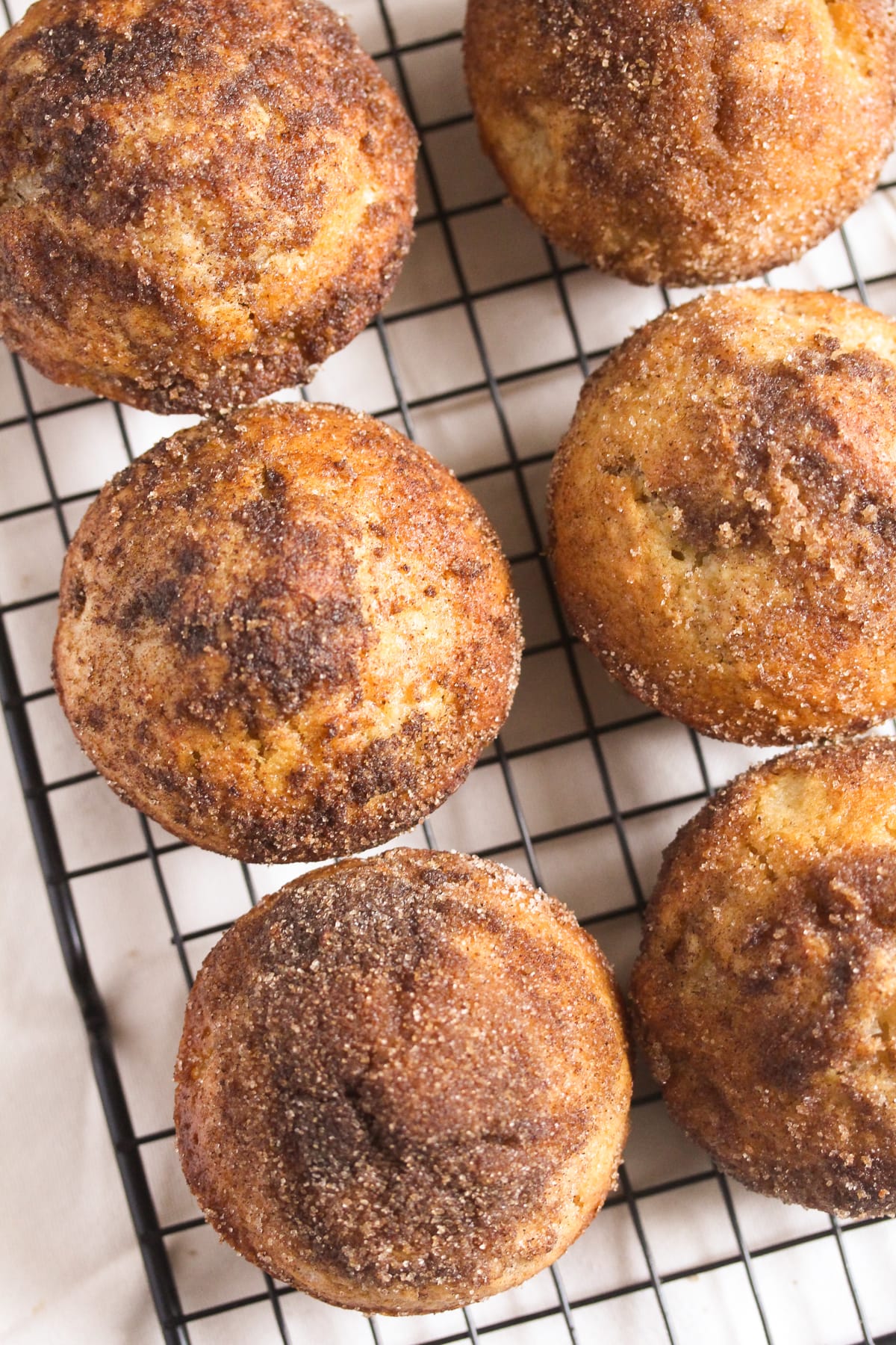 six cinnamon apple donut muffins cooling on a wire rack.