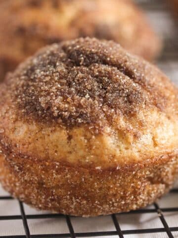 one cinnamon donut muffin on a wire rack, close up.