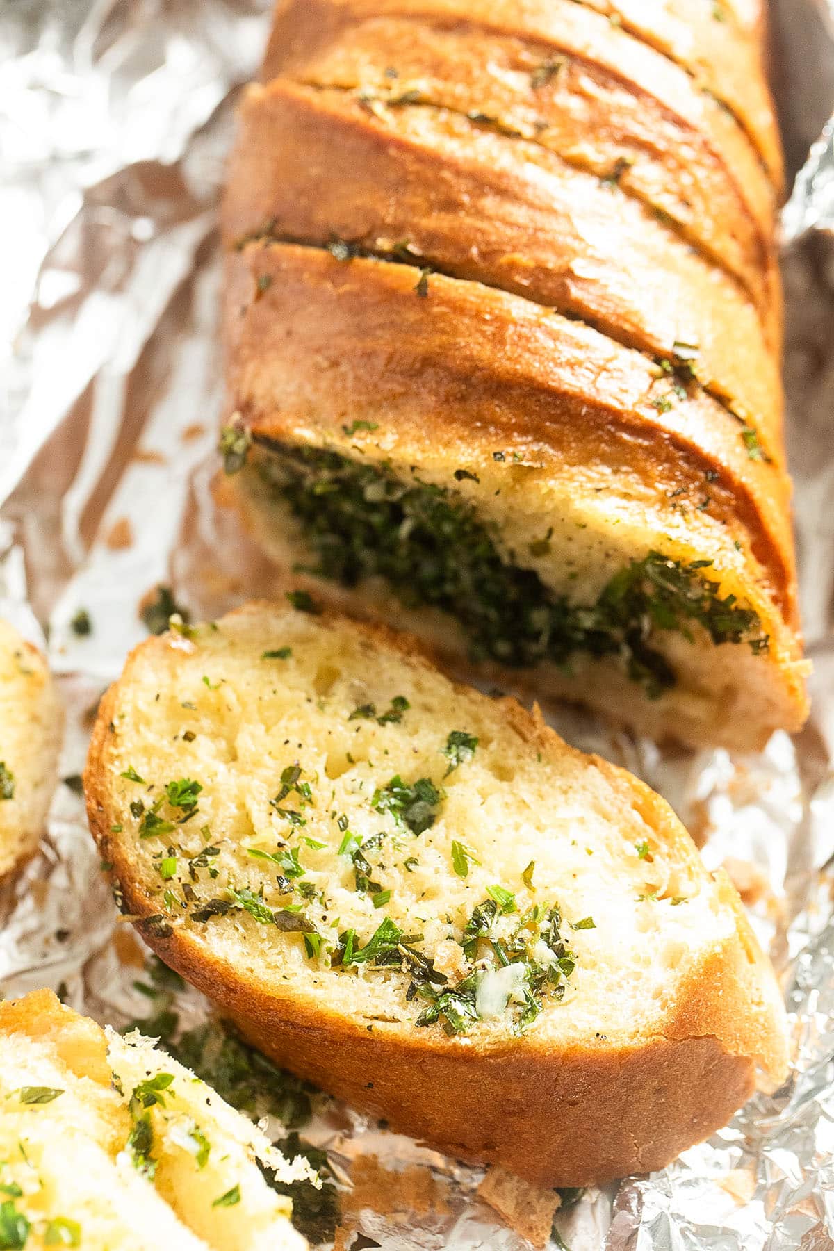 garlic bread made with baguette, garlic and fresh herbs sliced on foil.
