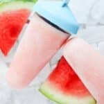 two pink greek yogurt and watermelon popsicles, watermelon pieces and ice cubes.