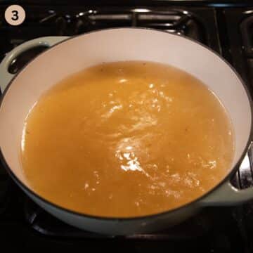 simmering broth for making german meatballs with sauce in a large dutch oven.