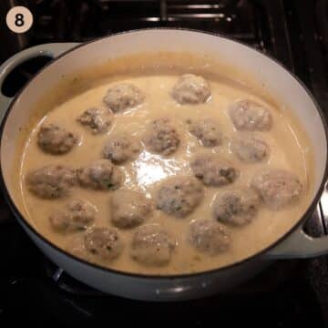 simmering german meatballs in white caper sauce in a dutch oven on the stovetop.