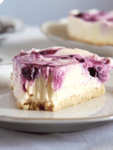 a slice of creamy no bake lemon curd cheesecake with fork marks at the top of the slice.