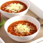 two bowls of soup with ground meat and grated cheese on top.
