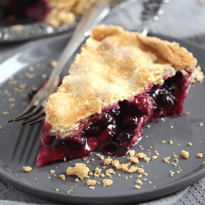 slice of rhubarb blueberry pie on a gray plate with a fork
