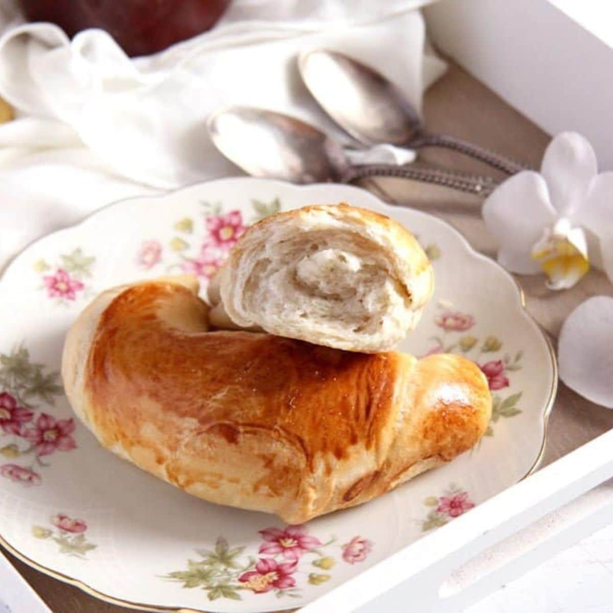 romanian crescent rolls, one split in the middle on a small plate.