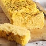 sliced romanian polenta loaf on a wooden cutting board.