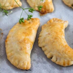 two spicy beef empanadas and a cilantro sprig with seeds.