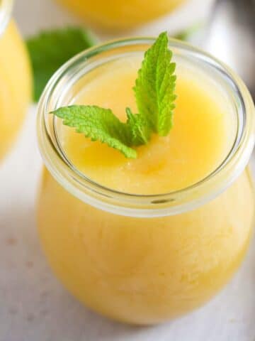 thermomix lemon curd garnished with mint leaves in a small jar.