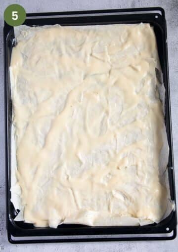 phyllo sheet covered with yogurt and egg mixture to make spinach pie on a baking sheet.