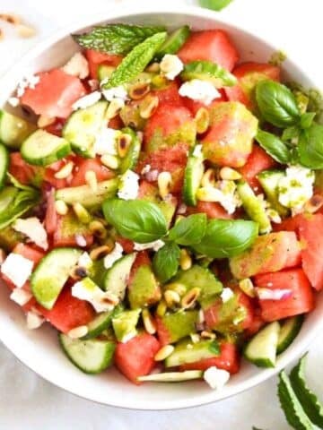 bowl with watermelon feta and balsamic salad with basil on top.
