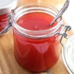smooth watermelon jam in a small jar with a spoon in it.