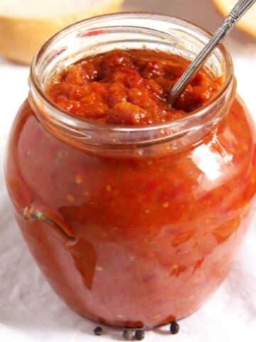 zacusca recipe or romanian eggplant spread in a jar with a spoon in it.