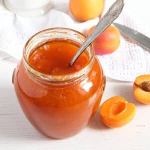 apricot jam without pectin in a jar and a few fresh apricots around it.