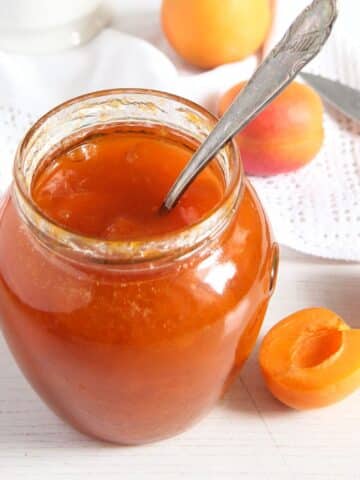 apricot jam without pectin in a jar and a few fresh apricots around it.