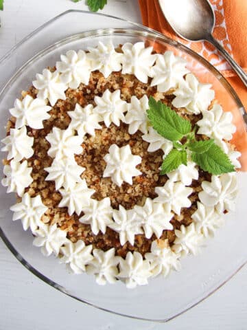 apricot trifle decorated with whipped cream in a bowl.