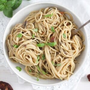 tangled aubergine spaghetti with basil leaves and a fork in a bowl.