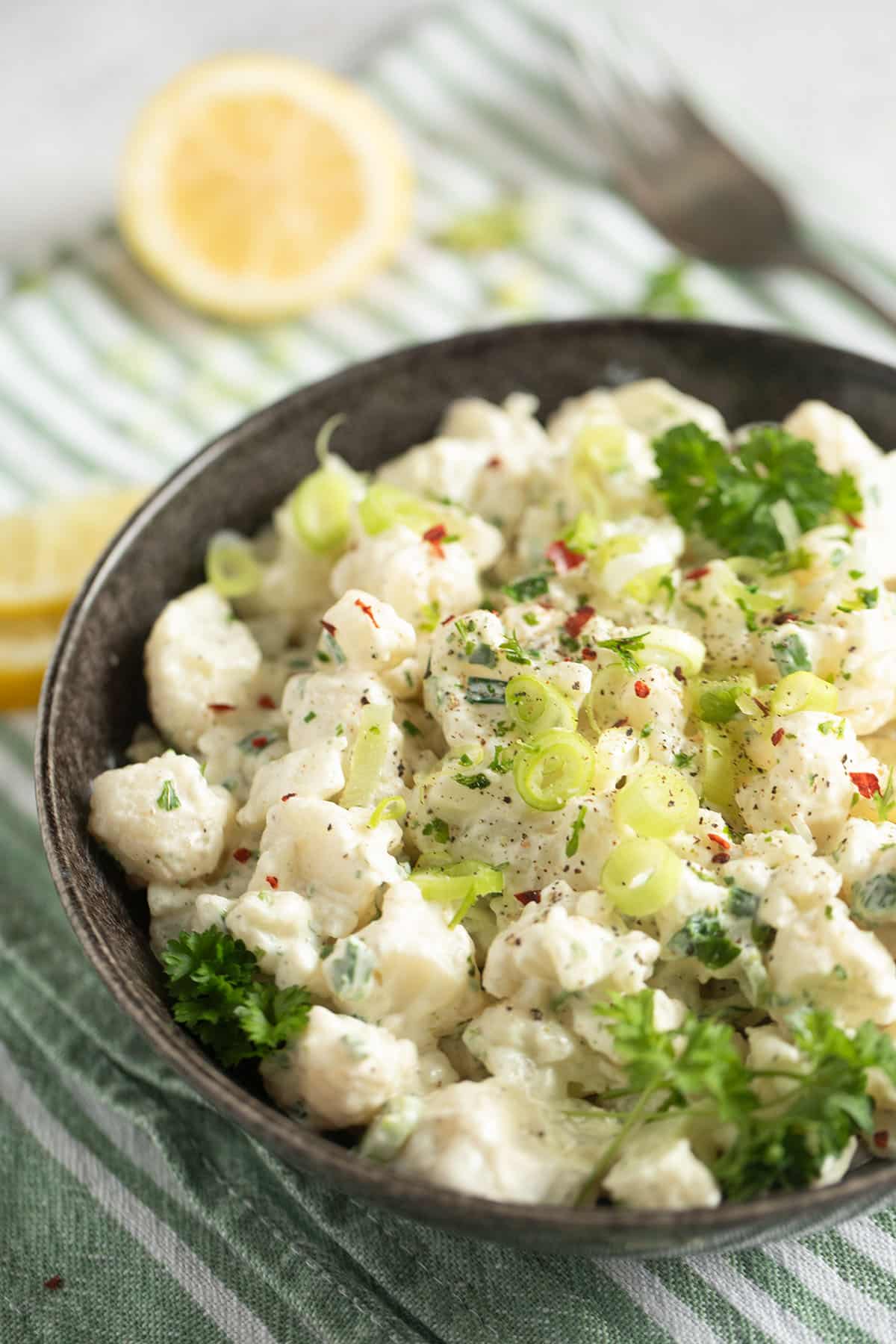 cauliflower mayo salad with green onions and parsley in a bowl.