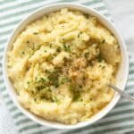 cauliflower and potato mashed in a bowl on a striped kitchen towel.