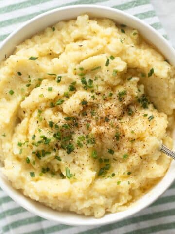 cauliflower and potato mashed in a bowl on a striped kitchen towel.