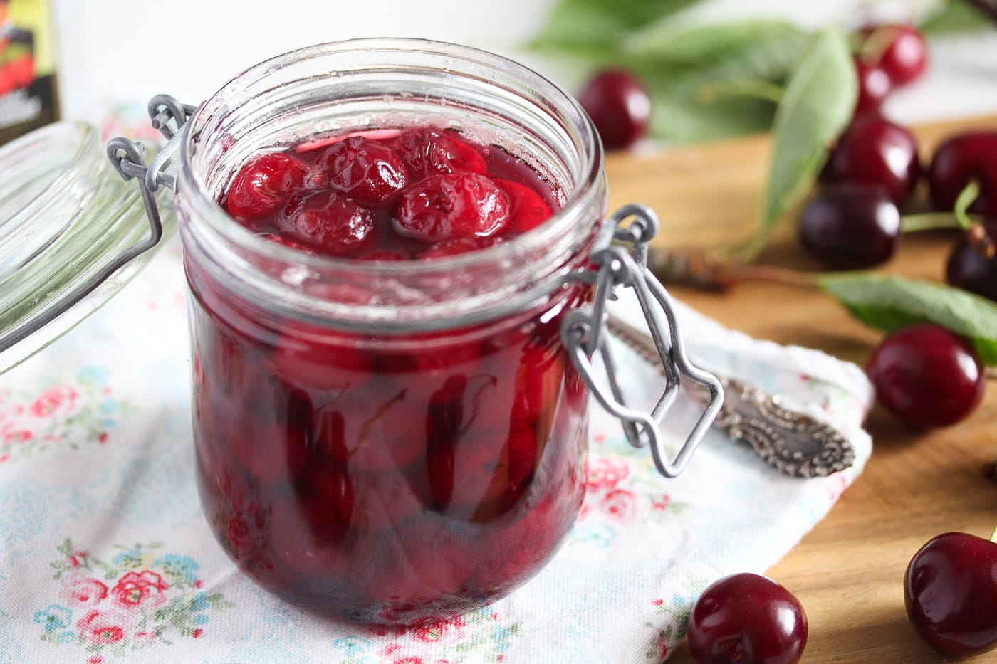 cherries preserved in alcohol in a jar with cherries in the background