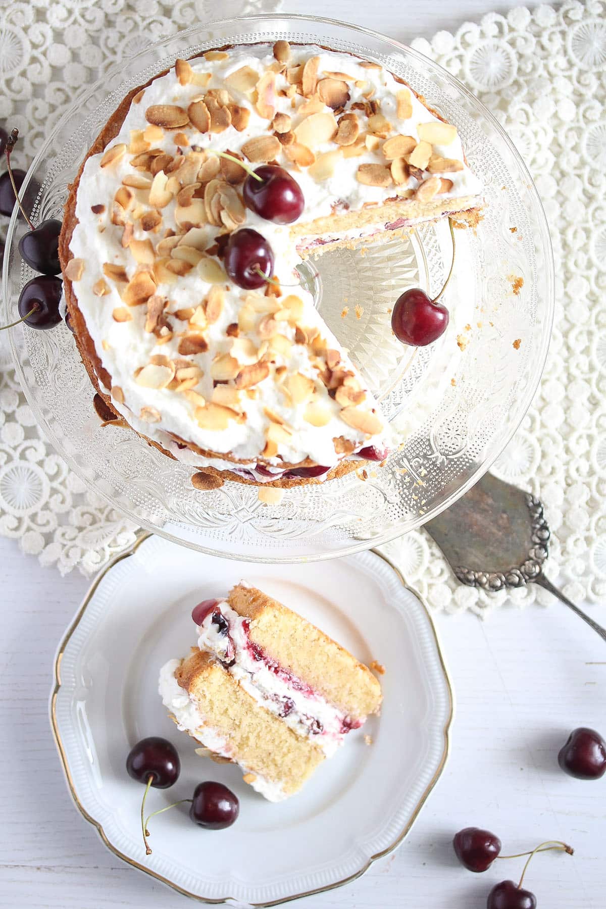 cherry bakewell cake on a platter and a slice on a plate.