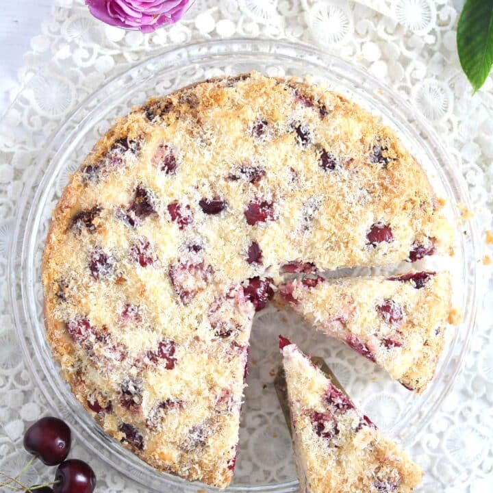 sliced cherry cake on a platter with a pink rose beside