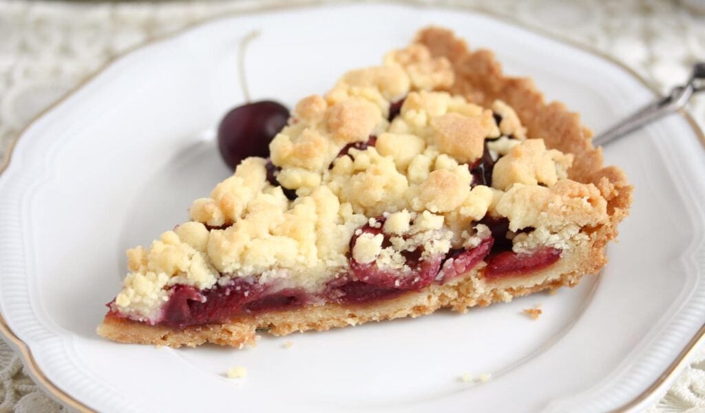sliced cherry pie with fresh cherries on a plate