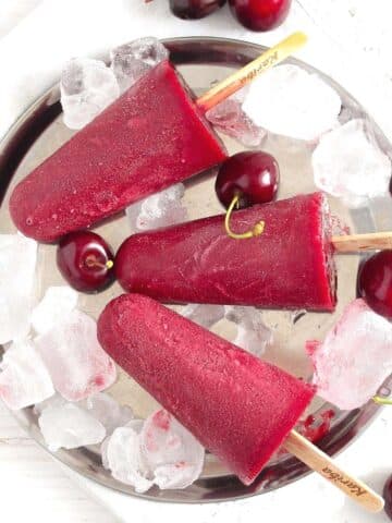 cherry popsicles on ice cubes on a platter