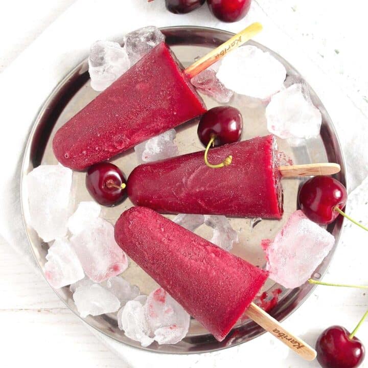 cherry popsicles on ice cubes on a platter