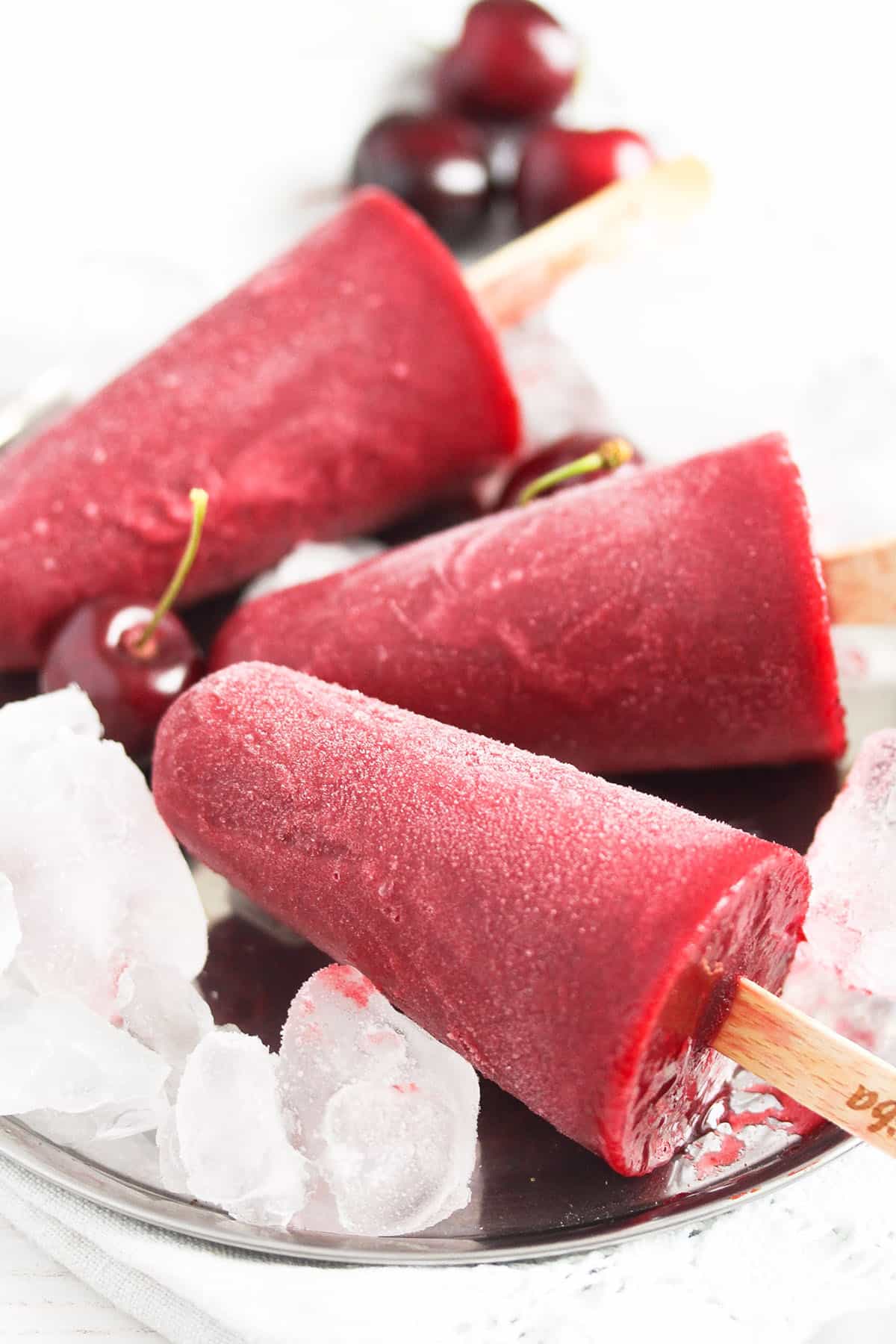 three cherry popsicles on ice cubes.