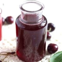 small bottle of cherry syrup on a white cloth.