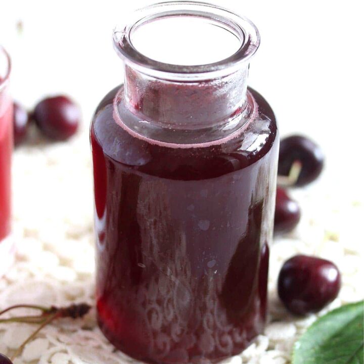 small bottle of cherry syrup on a white cloth.