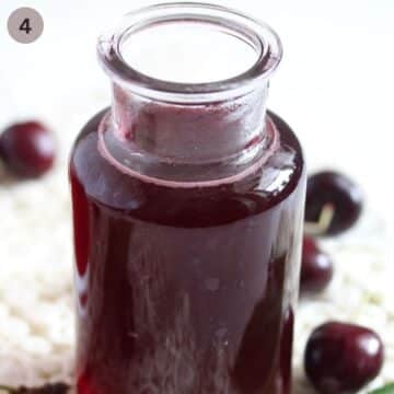 bottled cherry syrup and a few black cherries around it.