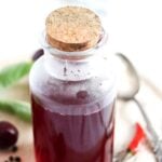bottle of infused cherry vinegar with a cork lid.
